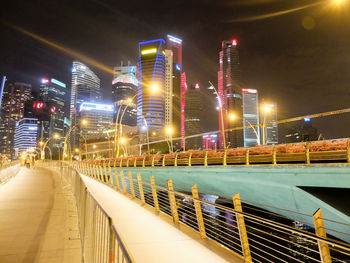 Illuminated bridge against buildings in city at night