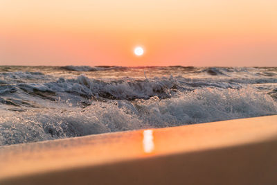 Scenic view of sea against sky during sunset with waves splashing at a low angle.