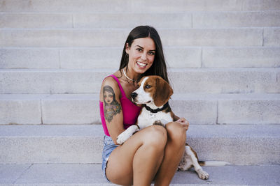 Portrait of woman with dog sitting on staircase