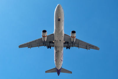 Low angle view of airplane against blue sky