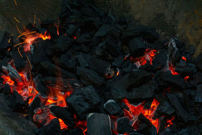 Coals with sparks in a huge old metal grill background