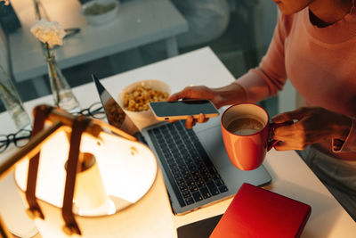 Midsection of woman using laptop on table