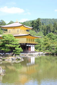 Built structure by lake and building against sky