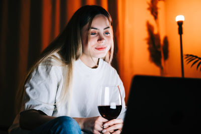 Portrait of a smiling young woman drinking glass