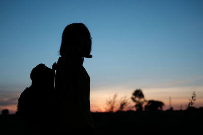 Silhouette woman standing against sky during sunset