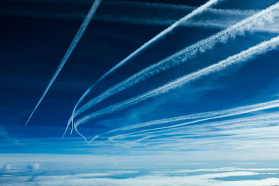 Low angle view of vapor trails against blue sky