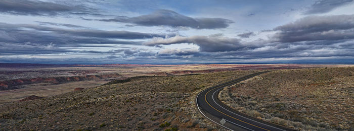 Road passing through landscape against cloudy sky