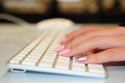 Cropped hands typing on keyboard at table