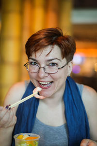 Portrait of smiling woman eating prawn at home