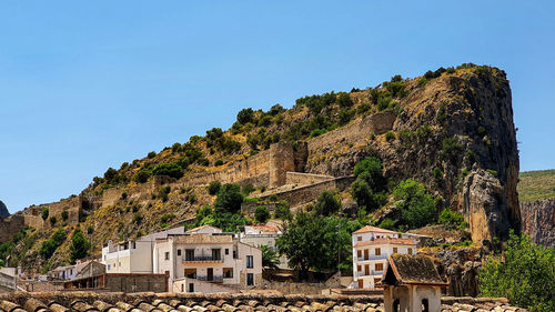 Trees, castle and buildings against clear sky