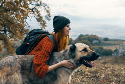 Young woman with dog looking away against sky