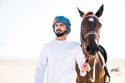 Man with horse walking against clear sky