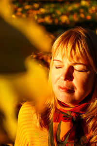 Closeup portrait of candid young caucasian blonde woman in colorful autumn park. bright stylish