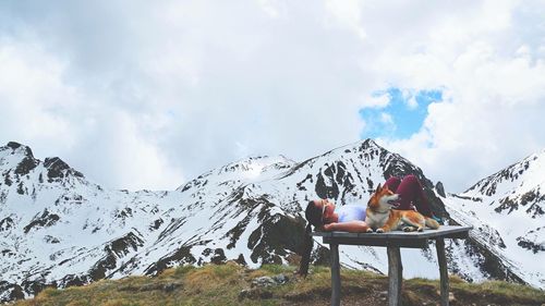 People sitting on snowcapped mountain against sky