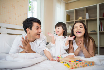 Family playing with toys on bed at home