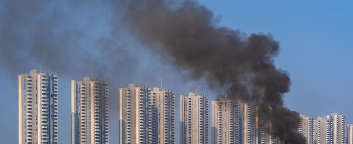 Smoke emitting from building against sky