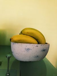 Close-up of bananas in bowl on table against wall