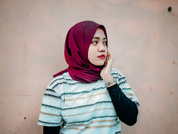 Portrait of young woman standing against wall