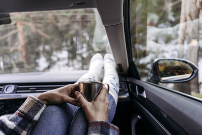Woman holding coffee cup and sitting in car
