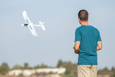 Rear view of man standing by airplane against sky