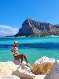 Young woman sitting on rock at beach