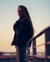 Young woman looking away against sky during sunset