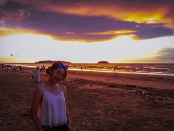 Boy standing on beach against sky during sunset