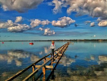 Pier in sea against cloudy sky