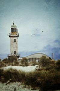 Warnemunde lighthouse at beach against sky