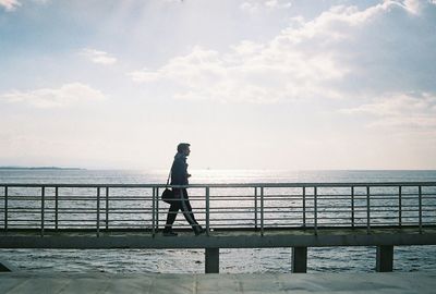 Woman standing on railing by sea