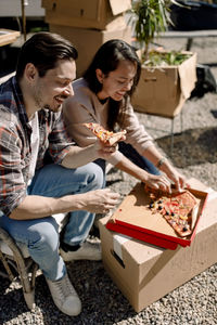 Smiling couple eating pizza while relocating in new house