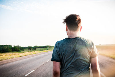 Rear view of man standing on road against sky