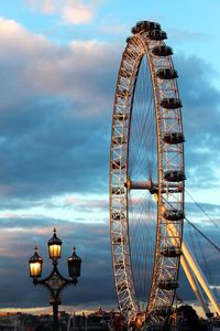 Low angle view of ferris wheel against cloudy sky