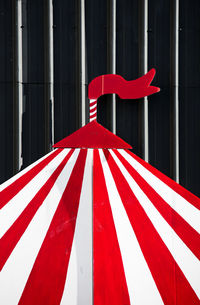 Close-up of red tent sculpture against corrugated iron