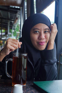 Portrait of indonesian muslim woman wearing black hijab with bokeh.