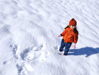 High angle view of girl standing on snow covered land