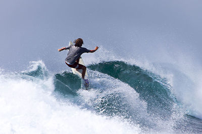 Rear view of man surfing on sea waves