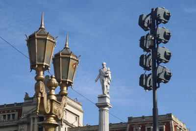 Low angle view of lighting equipment and general juan lavalle column at plaza lavalle against blue sky