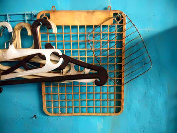 Close-up of coathangers and cooling racks hanging against blue wall