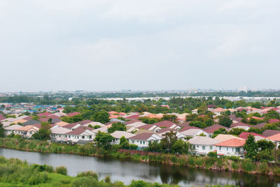 Houses by river amidst buildings against sky
