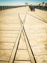 Surface level of boardwalk on pier against sky