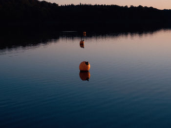 Silhouette person swimming in lake against sky