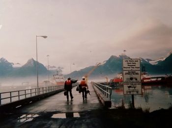 People walking on mountain by sea against sky