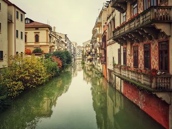 Canal amidst buildings against sky