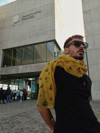 Portrait of young man standing against built structures