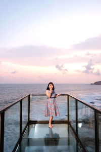 Full length of woman standing at beach against sky during sunset