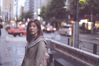 Portrait of woman standing on street in city