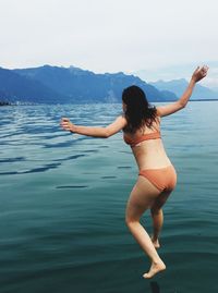 Rear view of young woman in sea against mountain