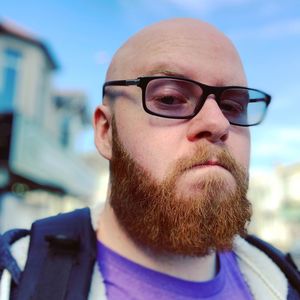 Portrait of bald man wearing eyeglasses against sky