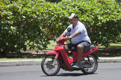 Side view of man riding motorcycle on road